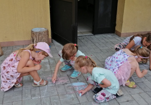 Dzieci rysują kredą na chodniku